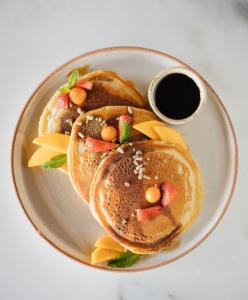 a plate of pancakes with fruit and a cup of sauce at Hotel Belmar in Monteverde Costa Rica