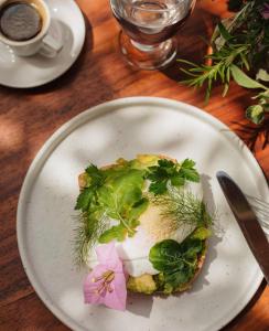 Un plato blanco con un sándwich con verduras. en Hotel Belmar, en Monteverde