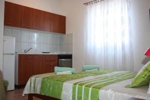 een slaapkamer met een bed met 2 stoelen en een keuken bij Studio Apartment Lenka in Milna