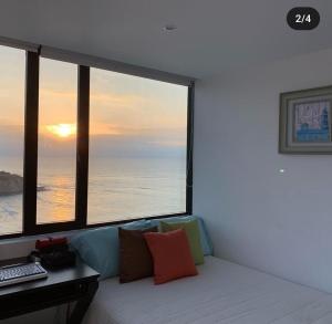 マンタにあるDepartamento vista al mar en Manta Poseidonのソファ、デスク、大きな窓が備わる客室です。