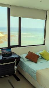 Departamento vista al mar en Manta Poseidon في مانتا: غرفة نوم مع سرير وجهاز كمبيوتر محمول على مكتب