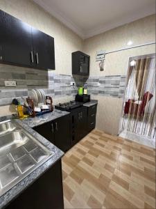 a kitchen with black cabinets and a wooden floor at Melford Homes in Lagos