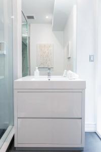 W białej łazience znajduje się umywalka i lustro. w obiekcie Elegant Downtown Home w mieście Toronto