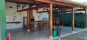 a pavilion with wooden beams and wooden tables and chairs at Excelente casa em condomínio fechado em Juquehy. 2 suítes, ar, piscina comum. in São Sebastião