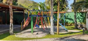 a playground in a park with palm trees at Excelente casa em condomínio fechado em Juquehy. 2 suítes, ar, piscina comum. in São Sebastião