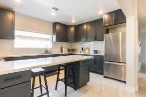 uma cozinha com armários pretos e um frigorífico de aço inoxidável em Spacious 5 BR Brand New HouseLAX/ SoFi/Kia/SpaceX/ em Inglewood