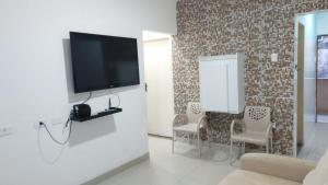 uma sala de estar com uma televisão de ecrã plano na parede em Apê Aconchegante no Recife