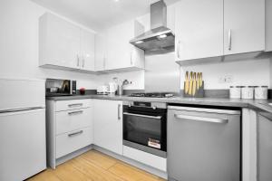 a kitchen with white cabinets and a stove top oven at Luxury 4 Bed House with En-suite, Games room, BBQ, On-site parking By Azura Nights in Birmingham