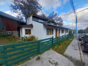 een wit huis met een groen hek bij Punto Sur-Barlovento -centro Ushuaia in Ushuaia