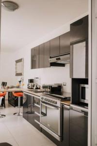 a kitchen with stainless steel appliances and orange chairs at Amplia Casa Moderna c/ Piscina y Lindos Jardines 
