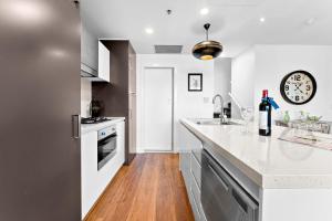 a kitchen with white counters and a wooden floor at Belle Escapes - Beach Retreat Townhouse Glenelg in Glenelg