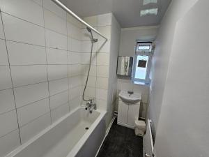 a white bathroom with a tub and a sink at Globe Rooms in London