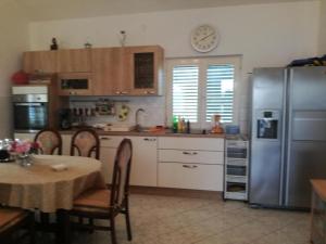 a kitchen with a table and a stainless steel refrigerator at Apartments by the sea Necujam, Solta - 21776 in Grohote