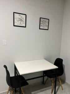 una mesa blanca y dos sillas contra una pared blanca en Departamento completo en Resistencia