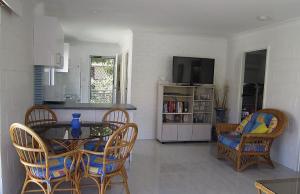 Una sala de estar con mesa y sillas y una cocina. en Blueys Beach Villa Manyana 14, en Blueys Beach