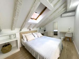 une chambre avec un lit blanc et une lucarne dans l'établissement Callao Suites, à Madrid