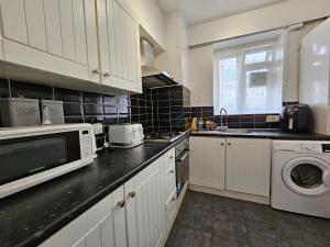 a kitchen with white cabinets and a washer and dryer at Globe Rooms in London