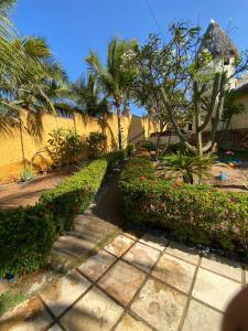 a garden with flowers and trees and a sidewalk at Pousada Capitólio 04 Canoa Quebrada in Canoa Quebrada