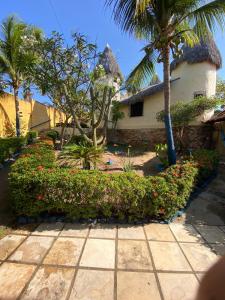 a house with palm trees and flowers and a sidewalk at Pousada Capitólio 04 Canoa Quebrada in Canoa Quebrada