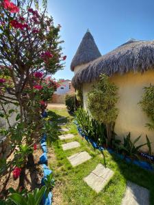 a path between two houses with a thatch roof at Pousada Capitólio 04 Canoa Quebrada in Canoa Quebrada