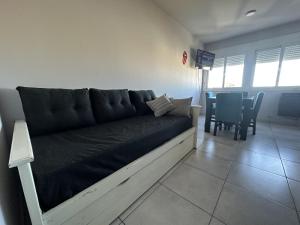a couch in a living room with a table and chairs at Departamento por día para 4 personas con cochera cubierta en Bahía Blanca in Bahía Blanca