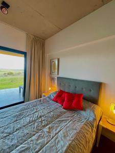 1 dormitorio con 1 cama grande y 2 almohadas rojas en Departamento Country Puerto del Águila- Lago los Molinos in 