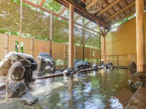 une piscine d'eau dans un bâtiment avec des rochers dans l'établissement Yukai Resort Hana-Saichoraku, à Kaga