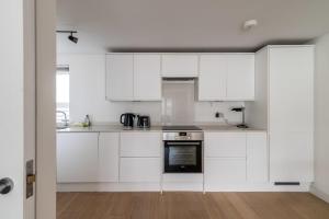 a kitchen with white cabinets and a stove at Belgravia Apartment 41 in London