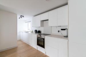 a white kitchen with white cabinets and black appliances at Belgravia Apartment 41 in London