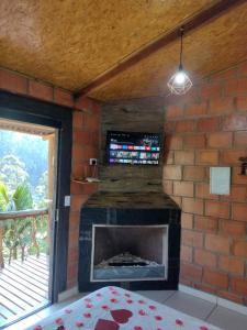 Una chimenea en una habitación con una pared de ladrillo en Chalés Fenix, en Santo Antônio do Pinhal