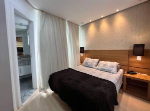 a bedroom with a large bed and a large window at Joia Rara - esquina com Raja Gabáglia in Belo Horizonte