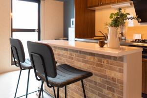 a kitchen with a counter with three stools at Bijou Suites Vogue in Osaka