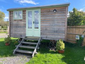 a tiny house with a door and stairs in the grass at The Hut in Langstone