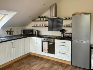 a kitchen with white cabinets and a stainless steel refrigerator at Chestnut Cottage in Wookey