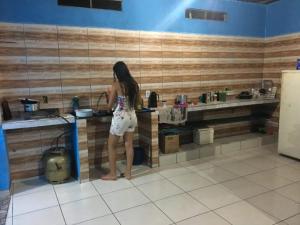 a woman standing in a kitchen preparing food at Quarto com ar condicionado, WiFi in Tareco