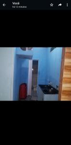 a blue room with a red suitcase and a sink at Quarto com ar condicionado, WiFi in Tareco