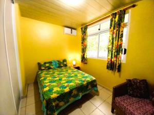 a bedroom with a bed and a window and a chair at MOOREA - Fare Taina Nui in Haapiti