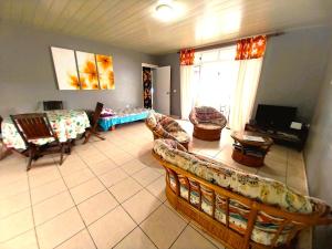 a living room with a couch and chairs at MOOREA - Fare Taina Nui in Haapiti