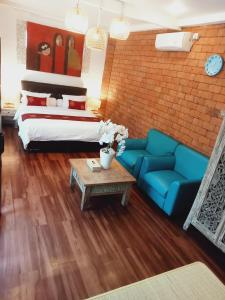 a living room with a bed and a blue couch at Buratwangi Tropis House in Kerobokan