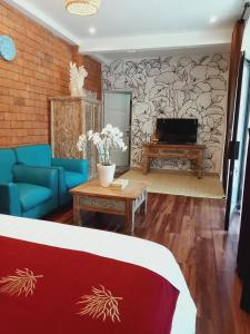 a living room with a couch and a tv at Buratwangi Tropis House in Kerobokan