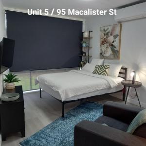 a bedroom with a bed and a tv and a couch at At Home Apartments in Sale