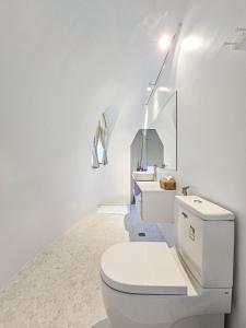 La salle de bains blanche est pourvue de toilettes et d'un lavabo. dans l'établissement 墾丁圓石灘 Kenting Pebble Beach, à Shizi