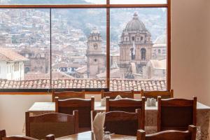 um quarto com uma mesa e cadeiras e uma grande janela em Hotel Amerinka em Cusco