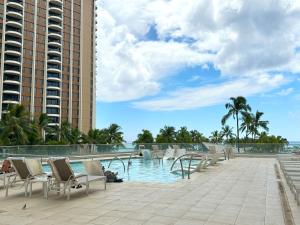 una piscina en un complejo con sillas y apartamentos en condominio en Ilikai Apt 308 - Spacious Studio with Stunning Ocean & Harbor Views en Honolulu