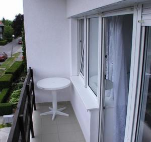 uma varanda com uma mesa branca e uma janela em Jartó Apartman em Harkány
