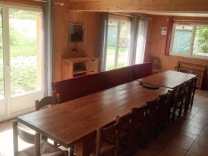 une grande table en bois et des chaises dans une pièce avec des fenêtres dans l'établissement Grand Chalet 5 pièces, 15 pers., cheminée, parking privé - Le Monêtier-les-Bains - FR-1-762-42, au Monêtier-les-Bains