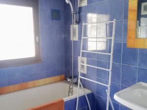 W wyłożonej niebieskimi kafelkami łazience znajduje się wanna i umywalka. w obiekcie Chalet Le Monêtier-les-Bains, 7 pièces, 25 personnes - FR-1-762-44 w mieście Le Monêtier-les-Bains
