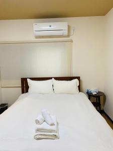 um quarto com uma cama branca e toalhas em *Fortune House*鶴見橋 花園町駅 *生活機能完備* 一軒家 *最大4人* em Osaka