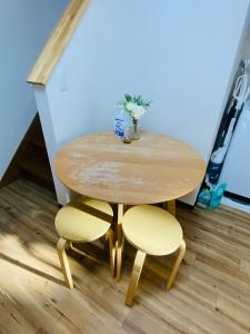 uma mesa de madeira com duas cadeiras e um vaso de flores em *Fortune House*鶴見橋 花園町駅 *生活機能完備* 一軒家 *最大4人* em Osaka