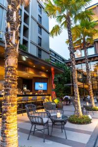 a patio with tables and chairs and palm trees at Maven Stylish Hotel Hua Hin in Hua Hin